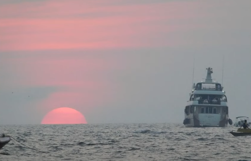 Ship sailing on the flat horizon at sunset