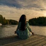 Person meditating and being present in the moment on a deck overlooking nature.