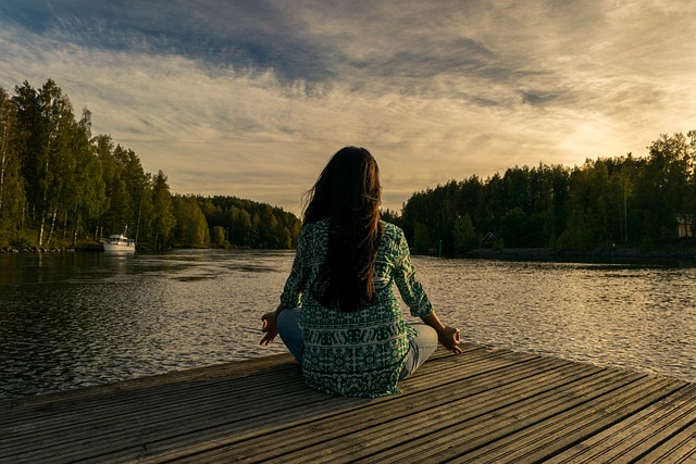 Person meditating and being present in the moment on a deck overlooking nature.