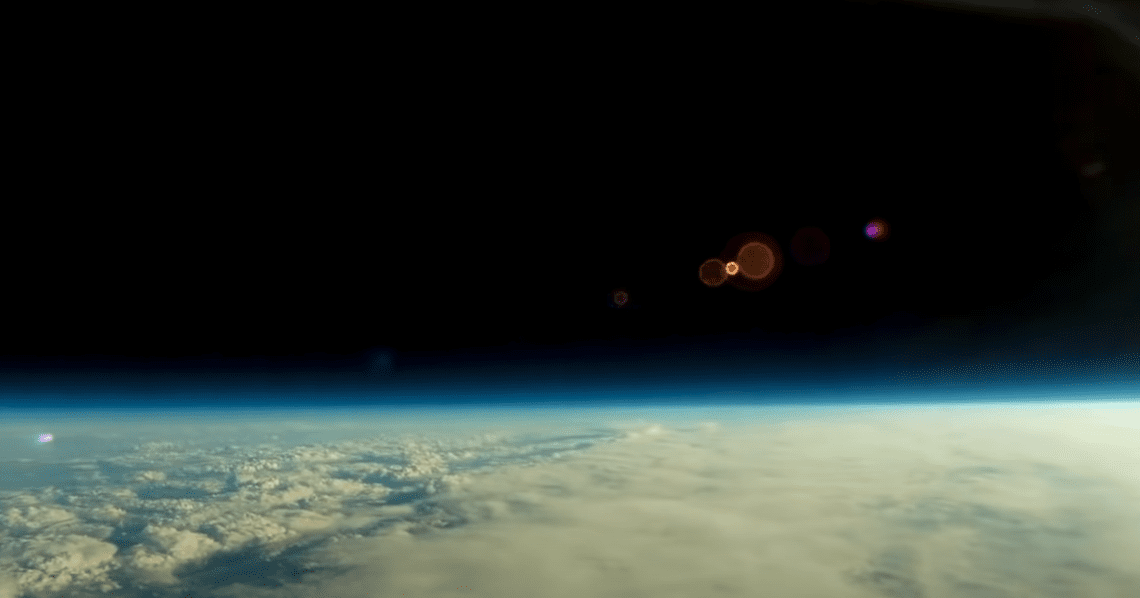 A panoramic view of a flat horizon from high up in the sky, with blue skies and clouds.