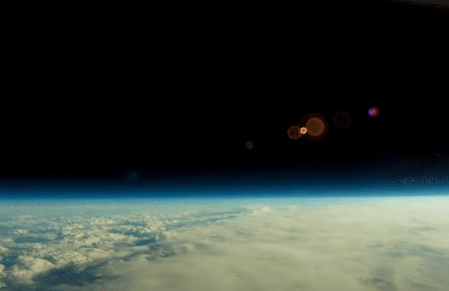 A panoramic view of a flat horizon from high up in the sky, with blue skies and clouds.