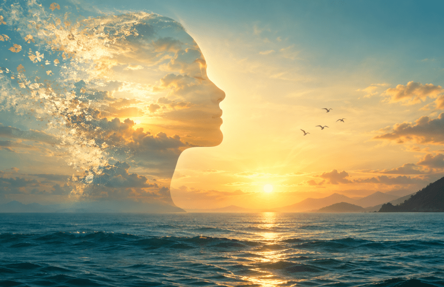 Conceptual human profile blending into golden light above a calm sea